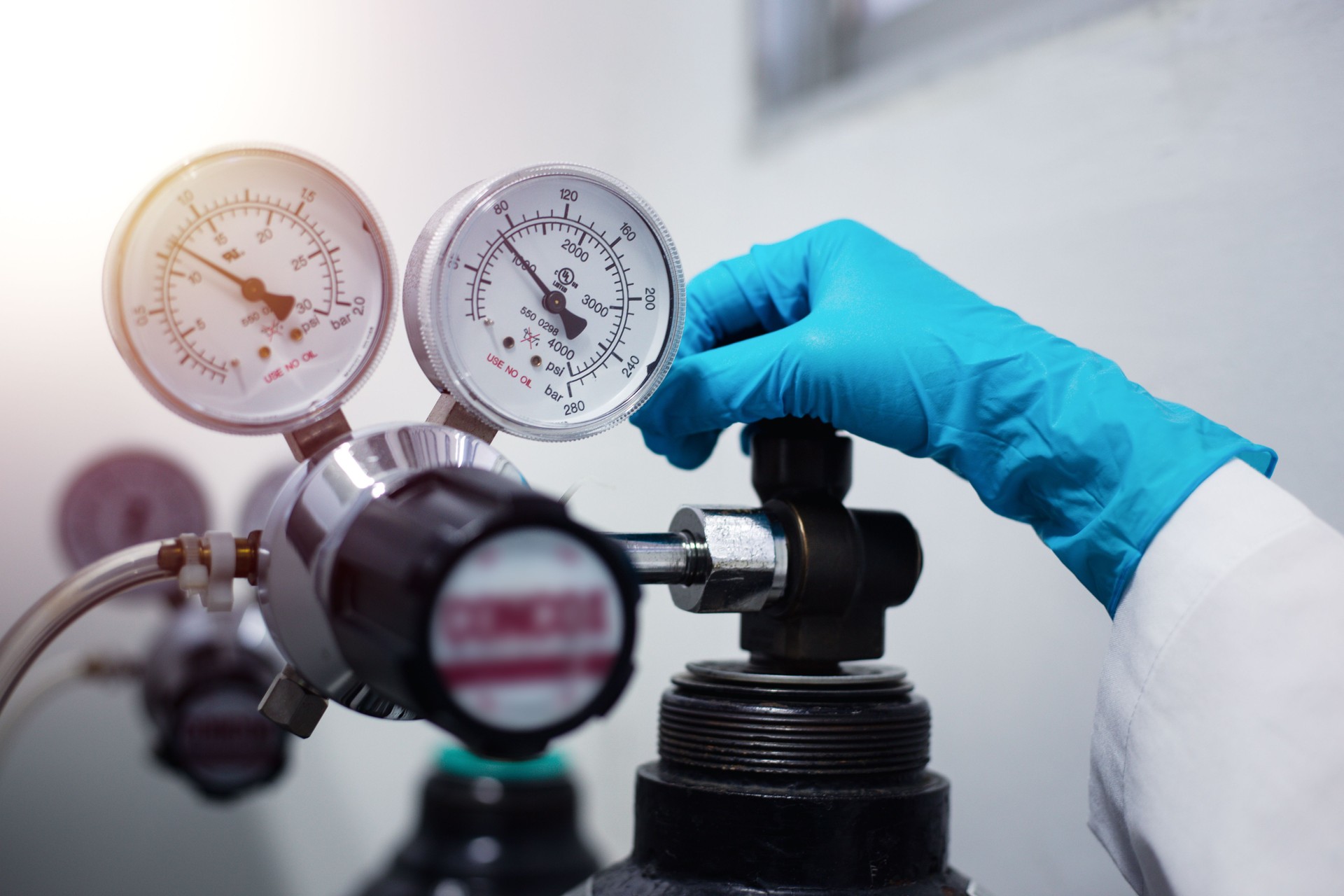 Closeup of a scientist's hand, checking gas from pressure gauge for a laboratory chromatography device during research.